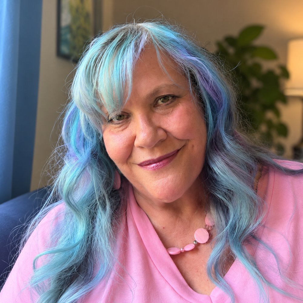 Janice (Jann) Holladay smiling, with long blue hair and a pink top
