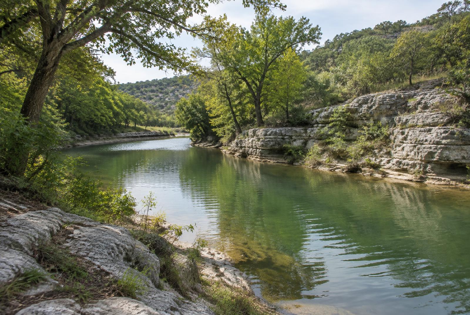 Green creek bordered by limestone and trees