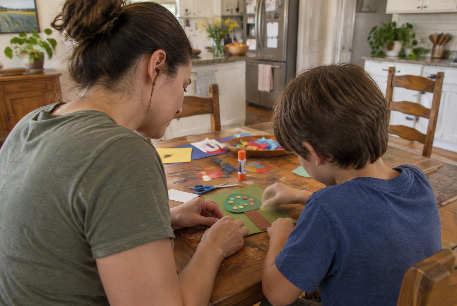 A parent and child working on a paper craft at home